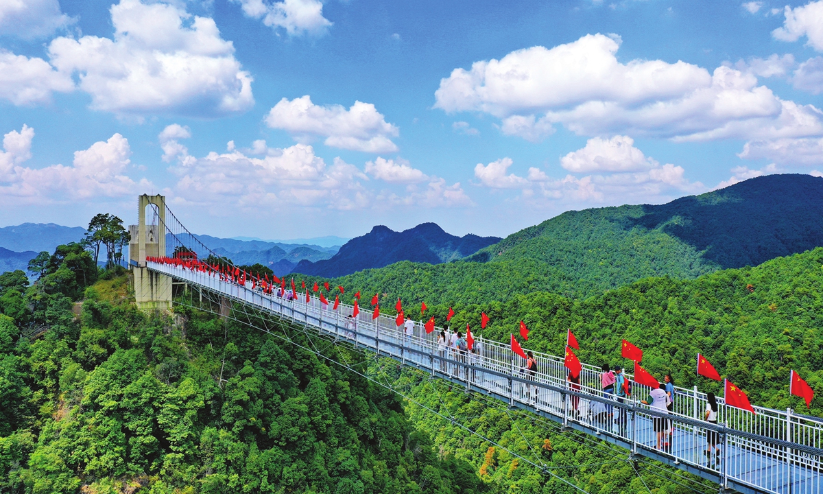 Tourists visit a glass-bottomed bridge in the Sanbai Mountain Scenic Area in East China's Jiangxi Province. Photo: VCG