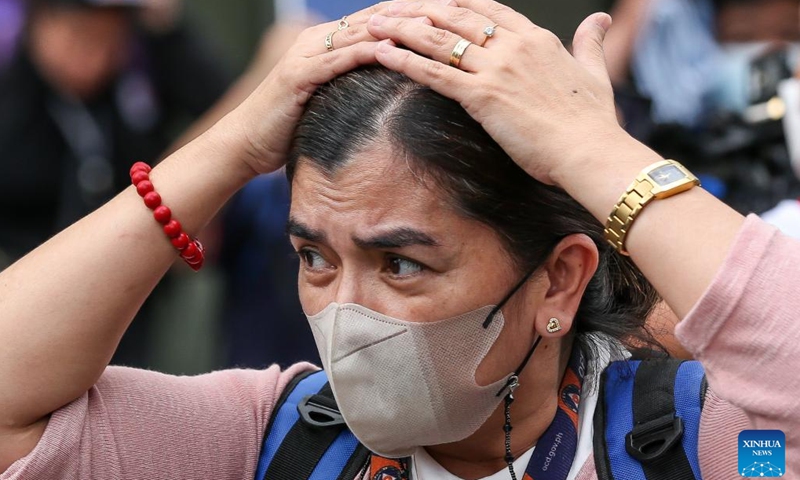 A woman protects her head as she evacuates from an office building during a national simultaneous earthquake drill at the Camp Aguinaldo in Quezon City, the Philippines, March 9, 2023.(Photo: Xinhua)