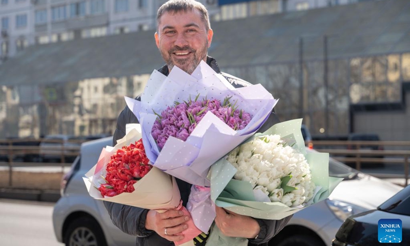 A man holds flower bouquets on a street in Vladivostok, Russia, March 8, 2023. Vladivostok, a city in the Russian Far East, is dotted with tulip stalls on the occasion of the International Women's Day.(Photo: Xinhua)
