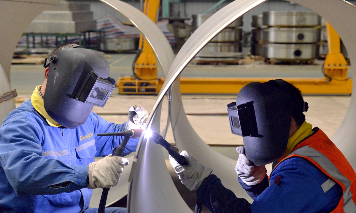 Two welders work together inside an industrial park in Taizhou, East China's Jiangsu Province on March 13, 2023. Electric cars, solar products and lithium batteries were China's export highlights in 2022, with the value of solar product exports growing 67.8 percent year-on-year, according to media reports. Photo: VCG