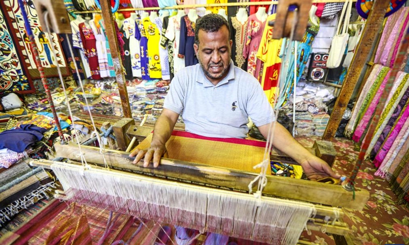 A man weaves with a loom to make handicrafts at Gharb Sohail village in Aswan, Egypt, on March 8, 2023. Gharb Sohail is a touristic Nubian village where visitors have a chance to know Nubians' unique traditions, crafts and food. Many people in the village now rely on the weaving industry to attract tourists.(Photo: Xinhua)