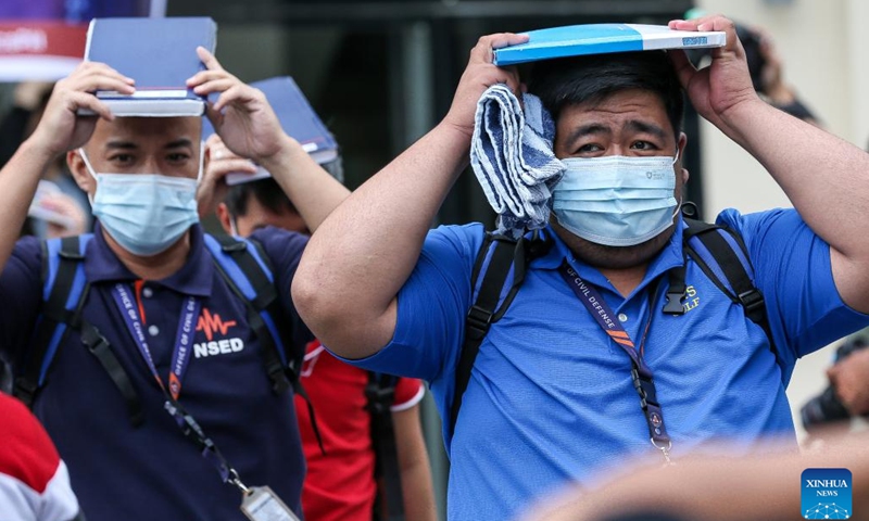 People protect their heads as they evacuate from an office building during a national simultaneous earthquake drill at the Camp Aguinaldo in Quezon City, the Philippines, March 9, 2023.(Photo: Xinhua)