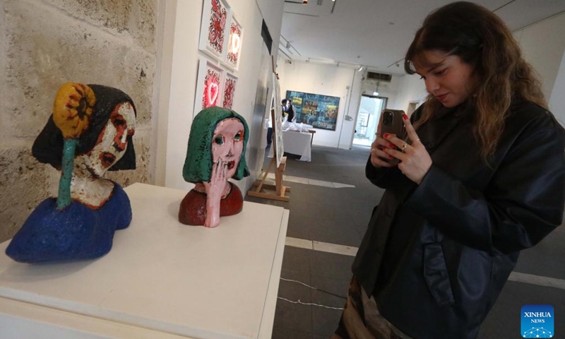 A visitor takes photos of artworks at an art exhibition at Beit Beirut in Beirut, Lebanon, on March 8, 2023. The art exhibition entitled Your Voice, Your Power was held here on Wednesday, on the occasion of International Women's Day.(Photo: Xinhua)