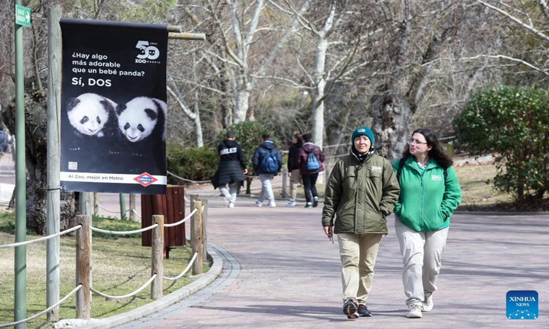 Visitors walk past a poster showing images of giant panda twins at Zoo Aquarium in Madrid, Spain, March 7, 2023. Thanks to close cooperation between Zoo Aquarium and China Conservation and Research Center for the Giant Panda, specialists and staff members managed to breed this extremely rare species in a country far away from its homeland. You You and Jiu Jiu were born to Hua Zuiba and her partner Bing Xing in September, 2021. This giant panda family is cordially deemed a bridge of friendship between Spain and China. (Photo:Xinhua)