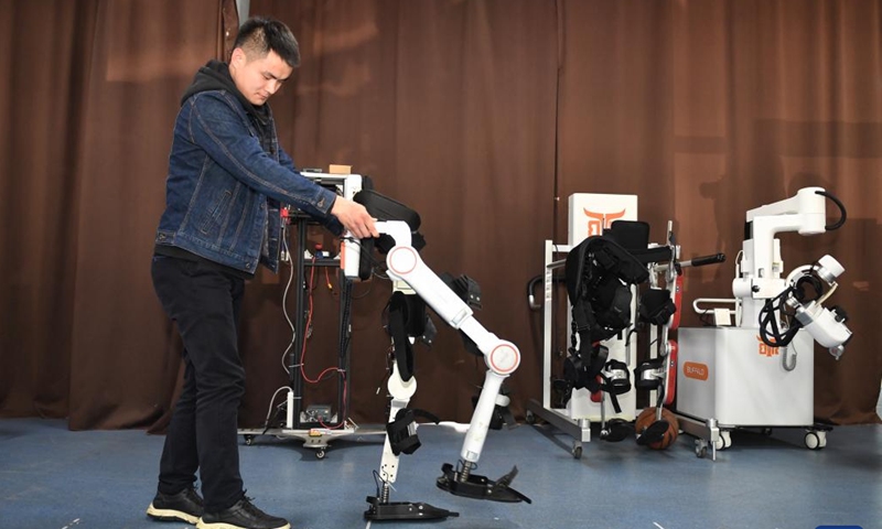 A scientific researcher from the Robotics Research Center at University of Electronic Science and Technology of China (UESTC) checks on an exoskeleton robot in Chengdu, southwest China's Sichuan Province, March 6, 2023.(Photo: Xinhua)