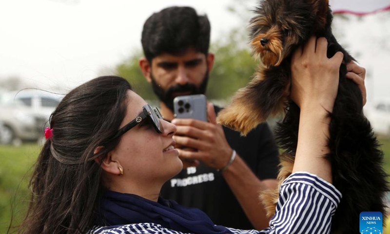 A woman plays with her dog during a dog show in Islamabad, Pakistan, on March 12, 2023.(Photo: Xinhua)