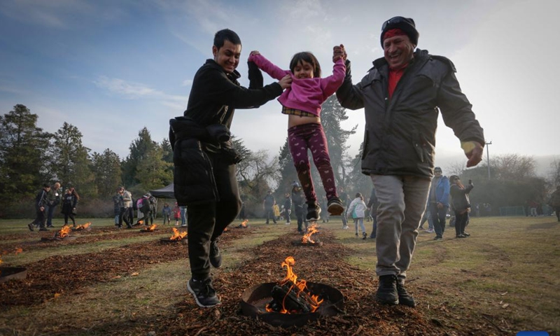 People help a young girl leap over a bonfire during the fire festival in celebration of Nowruz at Ambleside Park in West Vancouver, British Columbia, Canada, on March 14, 2023. The Persian New Year, or Nowruz, is celebrated by Canada's Iranian community with a concert, fires, and festivities in mid-March each year.(Photo: Xinhua)