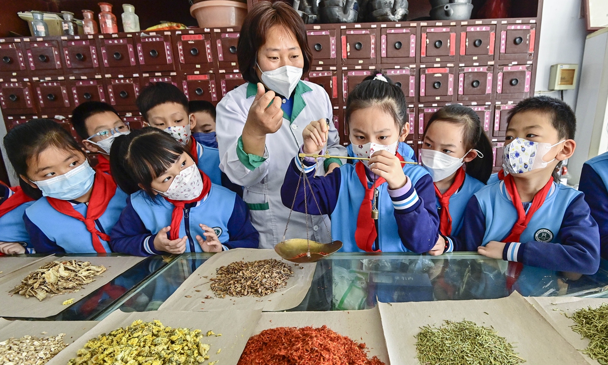 A student tries weighing traditional Chinese herbs under the guidance of a pharmacist in Qingzhou, East China's Shandong Province, on March 14, 2023. Students came to a nearby pharmacy to feel the charm of traditional Chinese medicine by identifying, weighing and processing herbs before the arrival of Chinese Medicine Day, which falls on March 17 each year. Photo: VCG