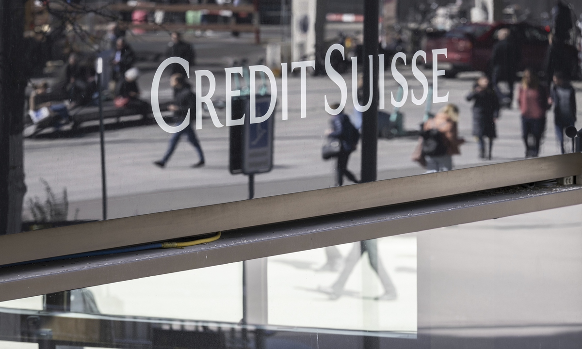 Pedestrians are re? ected on a window with the logo of Swiss bank Credit Suisse in Zurich, Switzerland, on March 16, 2023. Credit 
Suisse's shares soared 30 percent on the day after it announced it will move to shore up its ? nances by borrowing up to nearly $54 billion from the Swiss central bank. Photo: VCG