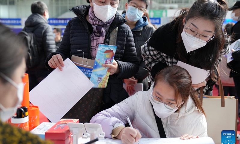 A job seeker (R front) fills in a form for employment at a job fair in Harbin, northeast China's Heilongjiang Province, March 18, 2023. More than 500 on-line and off-line recruiting events have been scheduled during this job fair, the largest of its kind in recent years held in the province, offering over 115,000 vacant positions in total. (Photo:Xinhua)