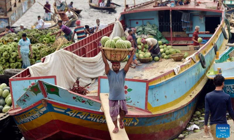 A worker unloads watermelons from a boat near a wholesale market in Dhaka, Bangladesh, March 21, 2023. Photo: Xinhua