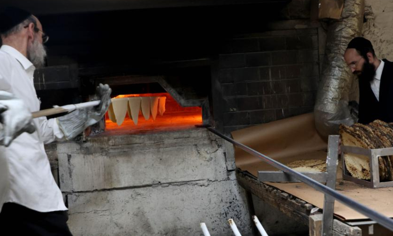 Ultra-Orthodox Jews prepare matza, traditional unleavened bread eaten during the upcoming Jewish holiday of Passover, in a bakery in Komemiyut village near Kiryat Gat of Israel, March 26, 2023. (Photo by Gil Cohen Magen/Xinhua)