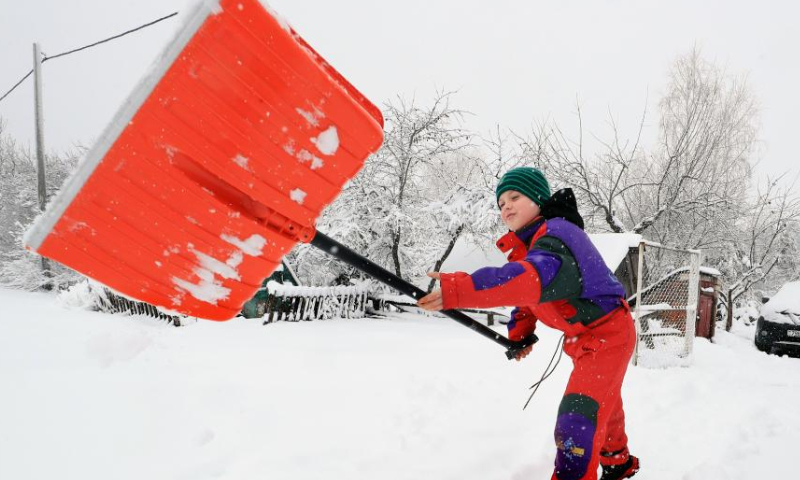A child removes snow in front of his home in Minsk, Belarus, March 28, 2023. Heavy snowfall swept parts of Belarus on Tuesday. (Photo by Henadz Zhinkov/Xinhua)