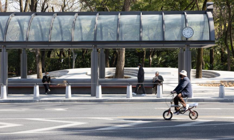 People wait for buses at a bus station near the Zhongshan Park in Shanghai, east China, March 13, 2023. With the construction of pocket parks, boulevard networks, green wedges, urban greenbelts and the like, Shanghai has been vigorously expanding its public ecological space. (Xinhua/Jin Liwang)