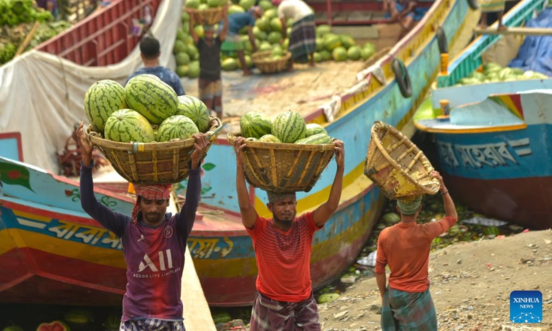 Workers unload watermelons from a boat near a wholesale market in Dhaka, Bangladesh, March 21, 2023. Photo: Xinhua