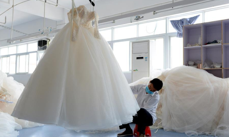 A worker trims wedding dress hemlines at a wedding dress producing company in Dingji Town of Lu'an City, East China's Anhui Province. Photo: Xinhua