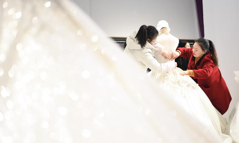 A shop owner arranges wedding dresses in a shop in Dingji township, Lu'an city, East China's Anhui Province. Photo: Xinhua