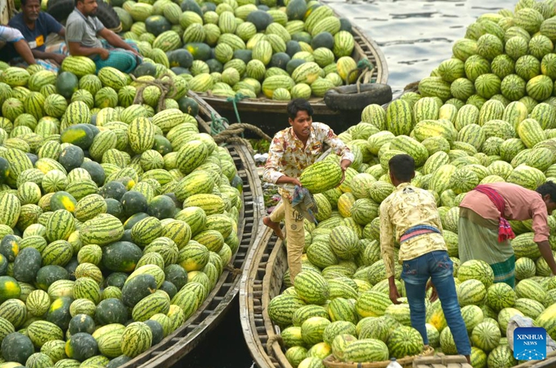 Vendors move watermelons on a boat near a wholesale market in Dhaka, Bangladesh, March 21, 2023. Photo: Xinhua