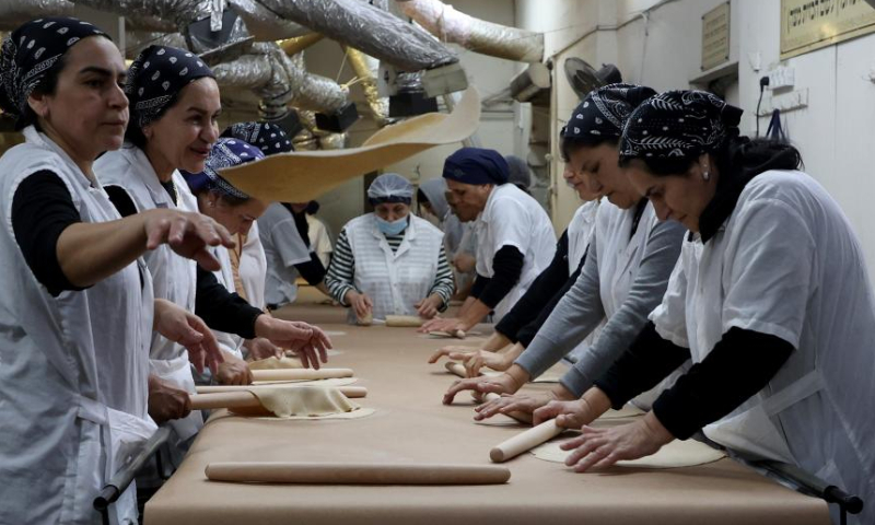 Ultra-Orthodox Jews prepare matza, traditional unleavened bread eaten during the upcoming Jewish holiday of Passover, in a bakery in Komemiyut village near Kiryat Gat of Israel, March 26, 2023. (Photo by Gil Cohen Magen/Xinhua)