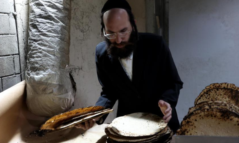 An Ultra-Orthodox Jew prepares matza, traditional unleavened bread eaten during the upcoming Jewish holiday of Passover, in a bakery in Komemiyut village near Kiryat Gat of Israel, March 26, 2023. (Photo by Gil Cohen Magen/Xinhua)