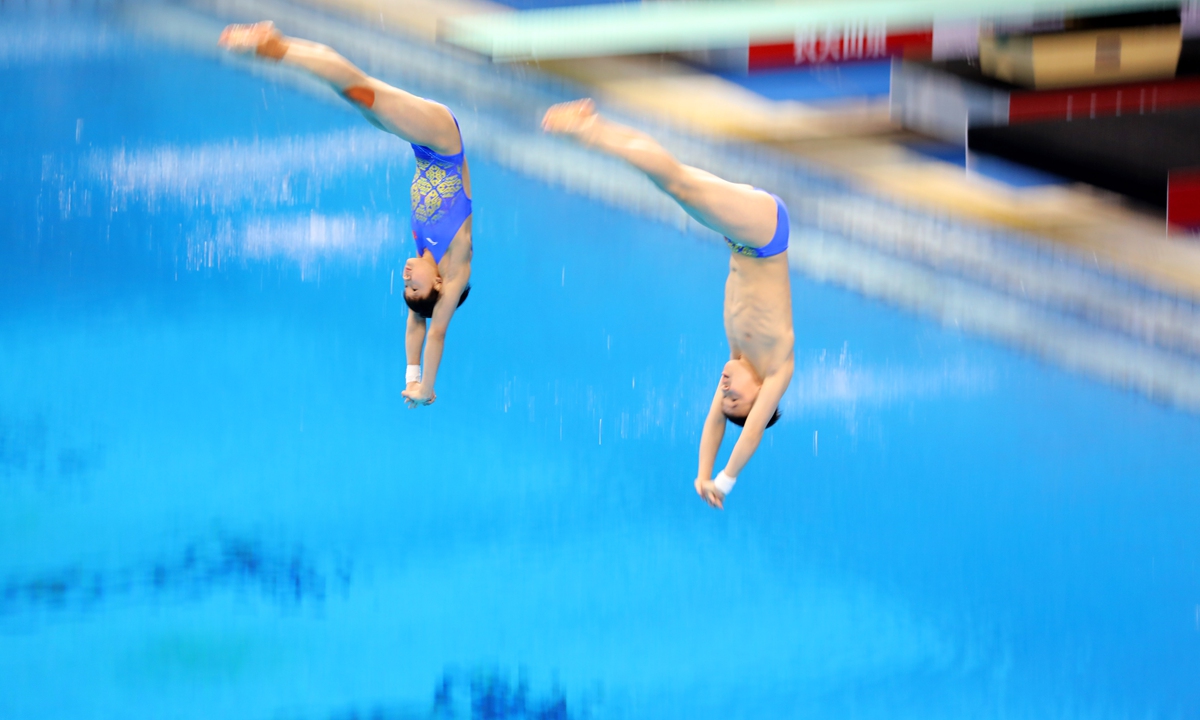 Athletes mid-dive in the mixed synchronized 10-meter platform diving competition on March 20, 2023.  Photo: Chen Xia/GT