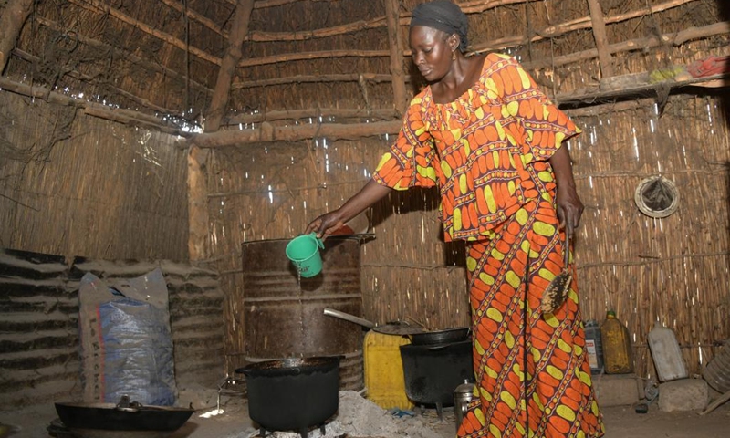 Nogaye yak, Mamadou Dieng's wife, cooks at home in Tenefoul Toucouleur Village, Diourbel, Senegal, March 20, 2023. Mamadou Dieng, 40, an employee of the Chinese construction company CGCOC Group Senegal Branch, has been responsible for maintaining a Chinese-aided well in Tenefoul Toucouleur Village. Checking the machine's functions and filling the engine with diesel, Dieng's work may seem simple and tedious, but means a lot to the locals.(Photo: Xinhua)