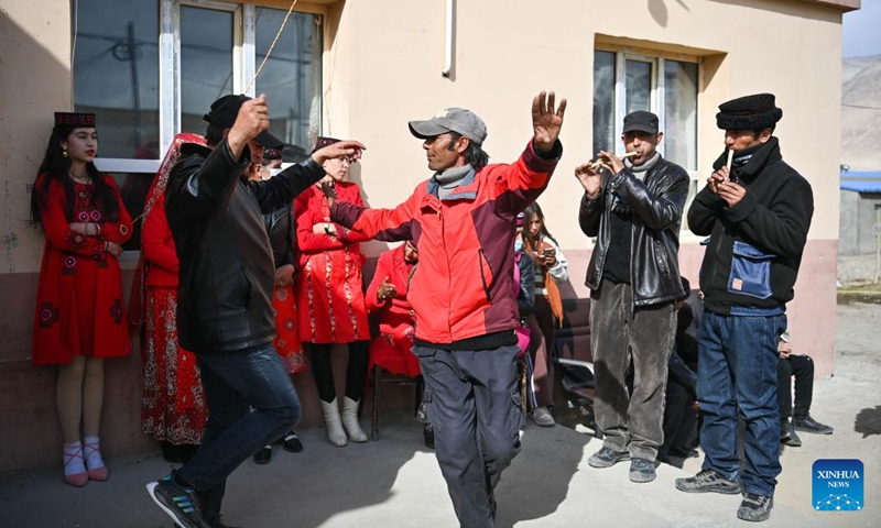 Relatives of Gulihan Jrbli play music instruments and dance in front of the bride's home in Taxkorgan Tajik Autonomous County, northwest China's Xinjiang Uygur Autonomous Region, March 18, 2023. In Taxkorgan Tajik Autonomous County, many young men and women prefer to get married in the spring season.(Photo: Xinhua)