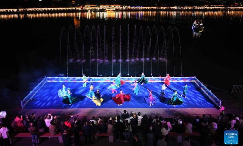 Tourists watch a performance at an ancient town in Langzhong, southwest China's Sichuan Province, March 20, 2023. In recent years, Langzhong has launched several live performances featuring local cultural elements to enhance tourists' night tour experience and boost the local cultural tourism.(Photo: Xinhua)