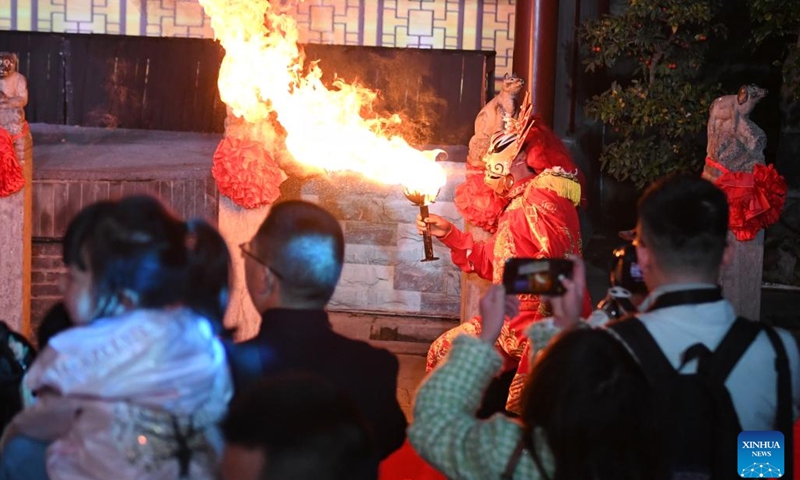 Tourists watch a performance at an ancient town in Langzhong, southwest China's Sichuan Province, March 20, 2023. In recent years, Langzhong has launched several live performances featuring local cultural elements to enhance tourists' night tour experience and boost the local cultural tourism.(Photo: Xinhua)