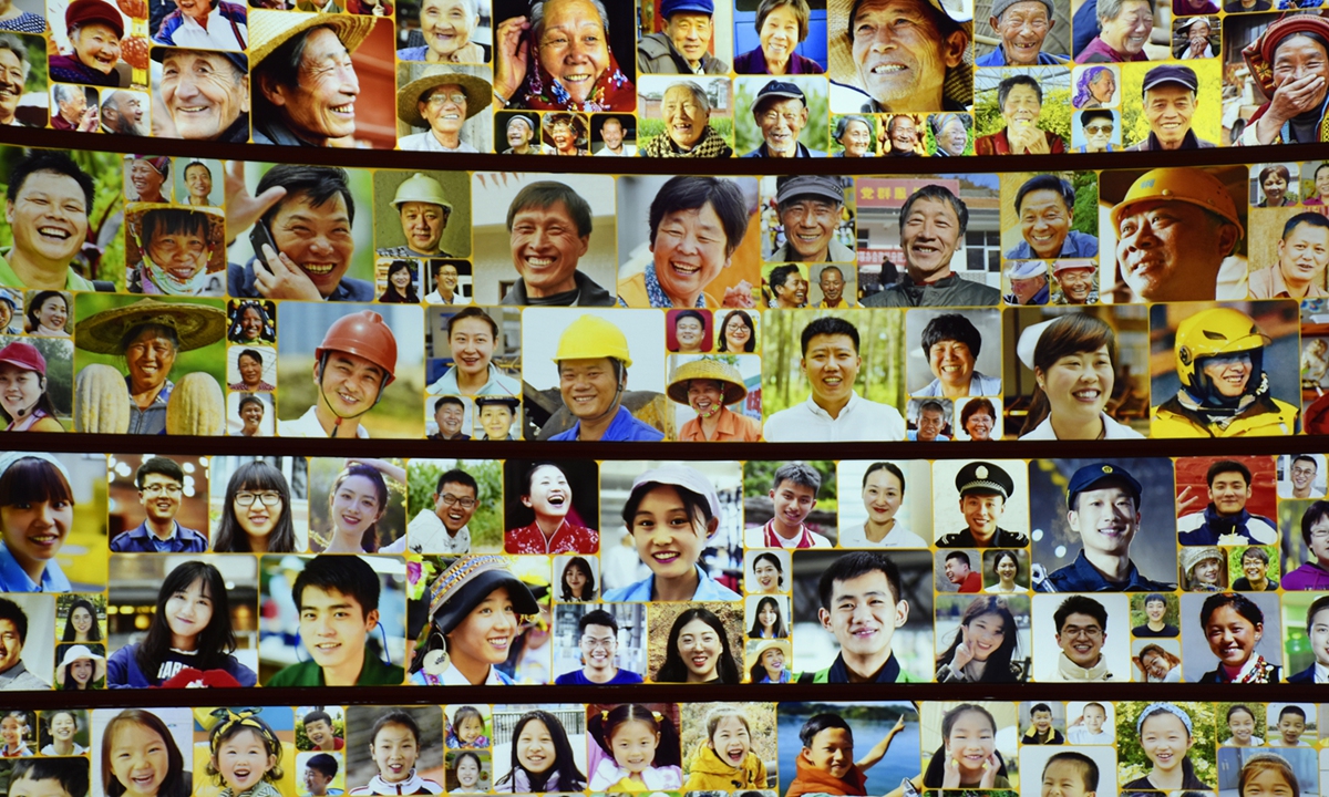 A photo taken on November 6, 2022 shows a wall displaying photos of smiling people at an exhibition themed 