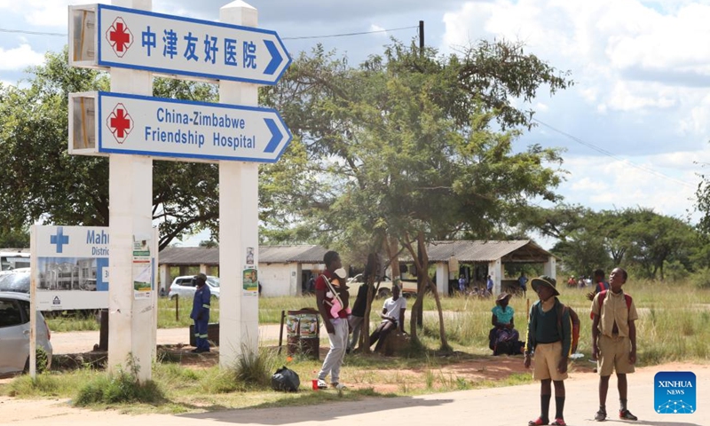 Villagers stand at a signpost pointing the direction of Mahusekwa Hospital in Mahusekwa, Mashonaland East Province, Zimbabwe, on March 24, 2023. (Photo:Xinhua)