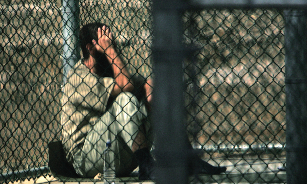 A detainee sits alone inside a fenced area during his daily time outside, at Camp 5 maximum security detention prison, Guantanamo Bay US Naval Base, on December 5, 2006. Photo: VCG