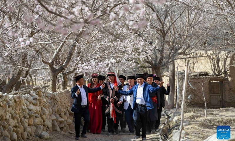 Local people perform in a traditional wedding ceremony for tourists in Bahrigzi Village of Tar Tajik Township, Akto County, northwest China's Xinjiang Uygur Autonomous Region, March 28, 2023. Tar Tajik Township, nestled in the hinterland of the Kunlun Mountains, is a key national rural tourism village under Akto County, northwest China's Xinjiang Uygur Autonomous Region. As the weather gets warmer, apricot flowers are in full bloom here. The magnificent natural scenery and unique folk customs attract many tourists.(Photo: Xinhua)