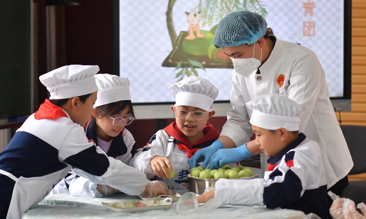 Students from a primary school learn to make qingtuan, a sweet green rice ball, under the guidance of a chef in Qingdao, East China's Shandong Province on April 3, 2023, before the arrival of the Qingming Festival, which falls on Wednesday. Qingtuan is a must-have offering for the ancestral rituals of the festival, which is also known as the 