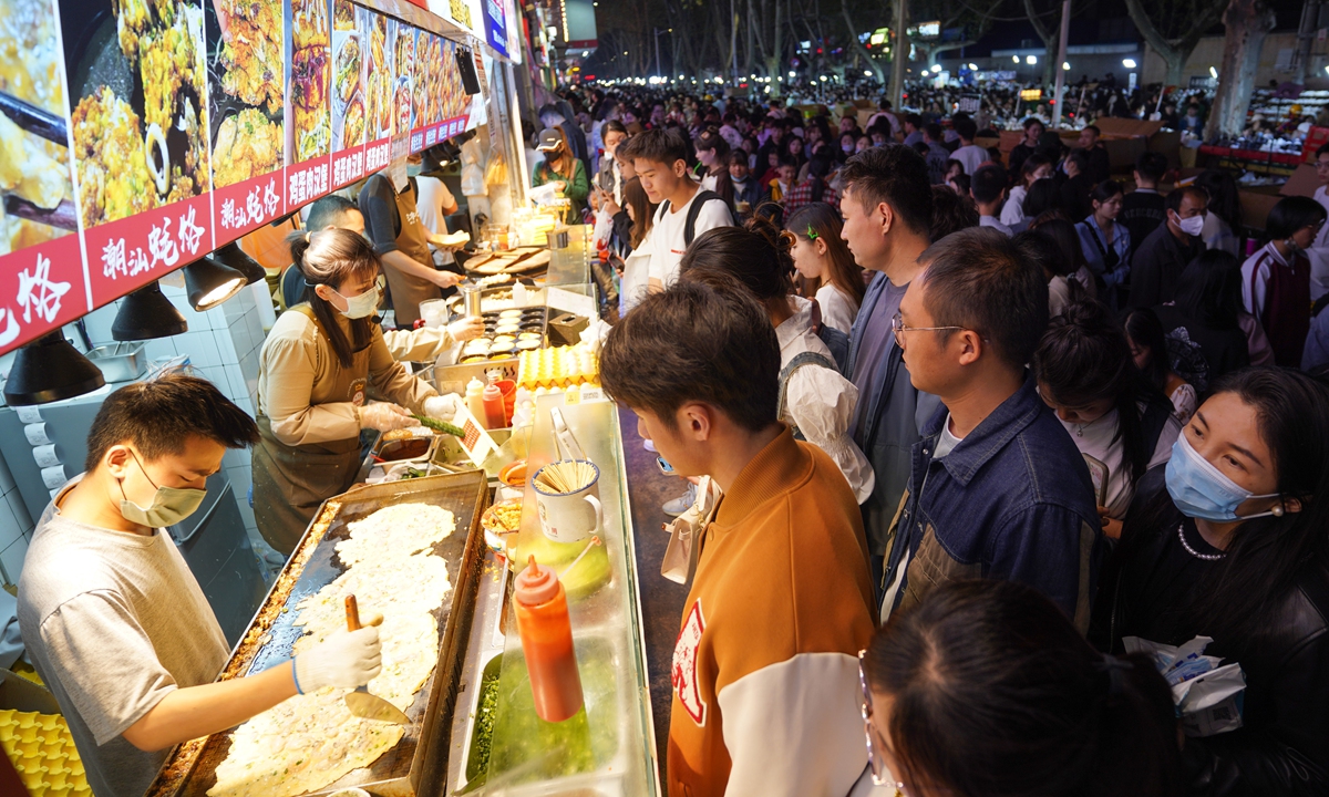 Young people wait in front of snack stalls in a night market in Zhengzhou city, Central China's Henan Province, on April 2, 2023. As the weather warms up, many provinces and cities across the nation have stepped up efforts to boost their night economies in order to spur consumption growth. Photo: VCG