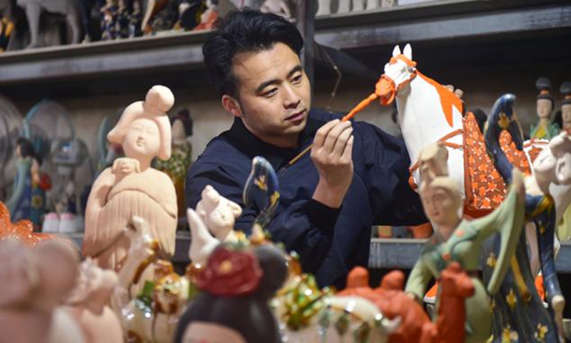 Zhang Yipeng glazes Sancai ceramics in his workshop in Luoyang city, central China’s Henan Province. (Photo:People's Daily Online)