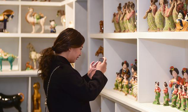 A female tourist takes pictures of Sancai products in Luoyang city, central China’s Henan Province. (Photo:People's Daily Online)