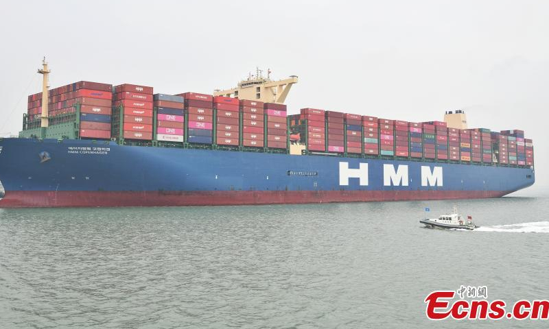 A patrol vessel sails next to a container ship, which prepares to dock at Tianjin Port, April 6, 2023. (Photo: China News Service/Tong Yu)