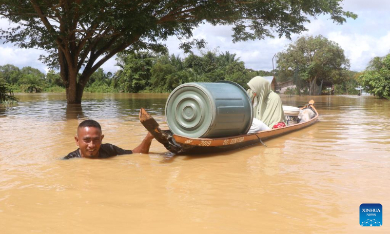 A man holding a wooden boat wades in flood water after heavy rain in Napai village in Aceh Barat district, Aceh Province, Indonesia, May 7, 2023. (Photo by Yulham/Xinhua)