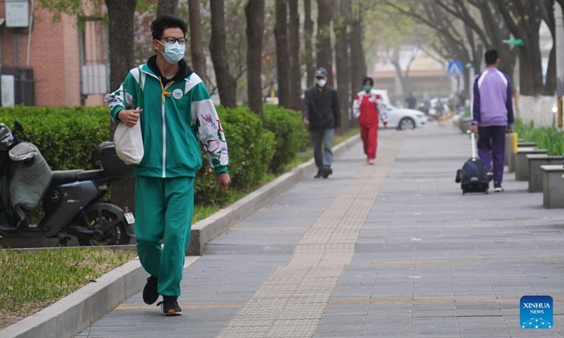 People wearing masks walk on a pavement in Haidian District of Beijing, capital of China, April 11, 2023. Floating sand and dust affected Beijing on Tuesday.(Photo: Xinhua)