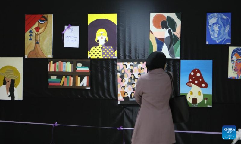 A woman attends an art exhibition organized by Hebron University to support students and market their paintings in the West Bank city of Hebron, on May 3, 2023. (Photo by Mamoun Wazwaz/Xinhua)