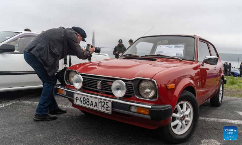 A man takes photos of a vehicle during an exhibition of classic cars in Vladivostok, Russia, May 13, 2023. (Photo by Guo Feizhou/Xinhua)