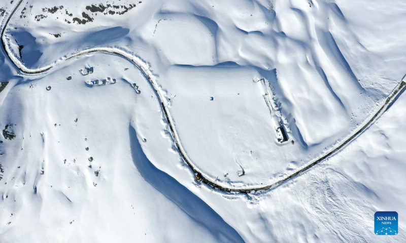 This aerial photo taken on May 10, 2023 shows the Dushanzi-Kuqa Highway winding past snowland in northwest China's Xinjiang Uygur Autonomous Region. (Xinhua/Hu Huhu)