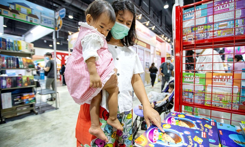 A mother carries her baby to select children's books at the Bangkok International Book Fair 2023 in Bangkok, Thailand, on March 30, 2023.(Photo: Xinhua)