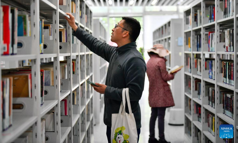 People look for books at a library in the culture center of Hexi District, north China's Tianjin, April 21, 2023. Hexi District in north China's Tianjin Municipality has offered convenient reading service to its readers by developing a reading service system. With the system, libraries in the district can share their resources and readers can borrow and return books by one stop. (Xinhua/Sun Fanyue)