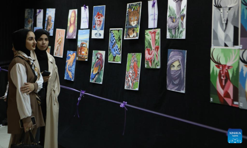 People attend an art exhibition organized by Hebron University to support students and market their paintings in the West Bank city of Hebron, on May 3, 2023. (Photo by Mamoun Wazwaz/Xinhua)