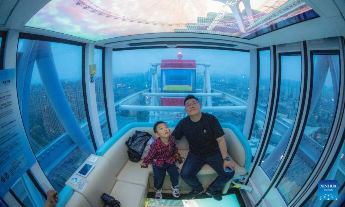 Tourists watch a video promoting Tianjin's cultural tourism on a newly installed screen while taking the Tientsin Eye Ferris wheel, in north China's Tianjin, April 27, 2023. The Tientsin Eye Ferris wheel, also known as the Tianjin Eye, one of the city's landmarks, has been renovated for the upcoming Labor Day holiday. Photo:Xinhua