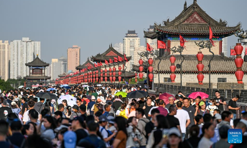 People visit the ancient city wall scenic spot in Xi'an, northwest China's Shaanxi Province, April 30, 2023. China has witnessed a travel boom during this year's five-day May Day holiday. (Photo by Zou Jingyi/Xinhua)
