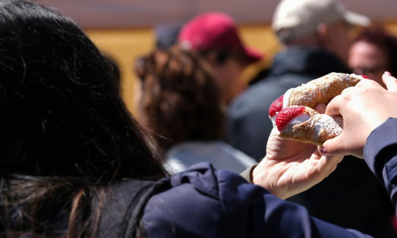A woman eats food made with strawberries in Mgarr, Malta, on April 16, 2023. Malta on Sunday held its annual strawberry festival in Mgarr, a picturesque agricultural village in north Malta. (Photo by Jonathan Borg/Xinhua)