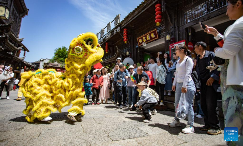 Tourists watch lion dance at the Hong'an ancient town in Xiushan Tujia and Miao Autonomous County, southwest China's Chongqing, April 30, 2023. China is witnessing a travel boom during this year's five-day May Day holiday. (Photo by Hu Cheng/Xinhua)